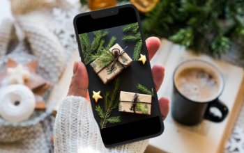 Hand-holding-a-smartphone-with-Christmas-presents